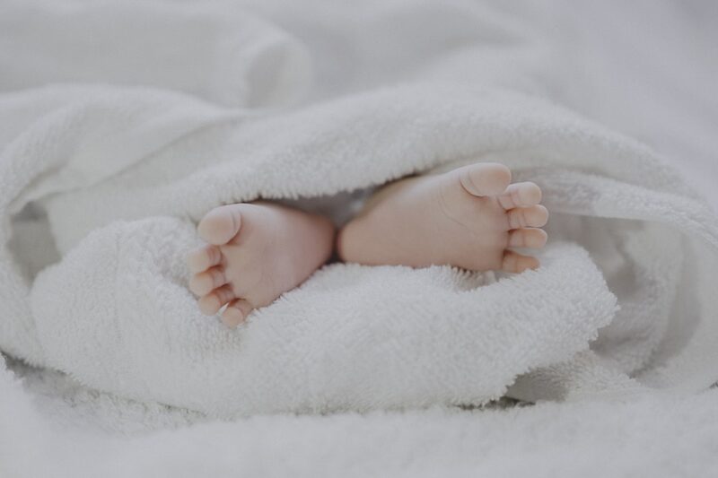 Newborn baby feet wrapped in a soft white blanket